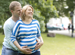 A couple expecting a child having a good time outdoors