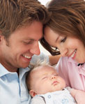 Close shot of young couple smiling down at sleeping infant