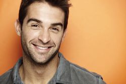 Man smiling against orange background.          