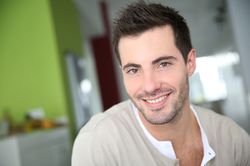 A man with short brown hair sitting in front of a green wall