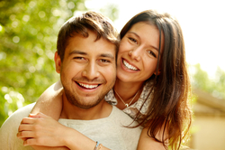 Couple smiling and hugging outdoors.          