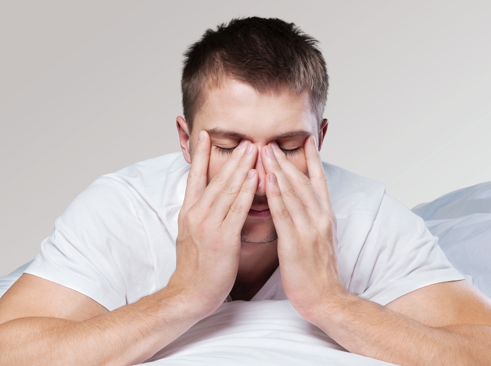 A man with his hands on his face, looking stressed out, which could affect his fertility