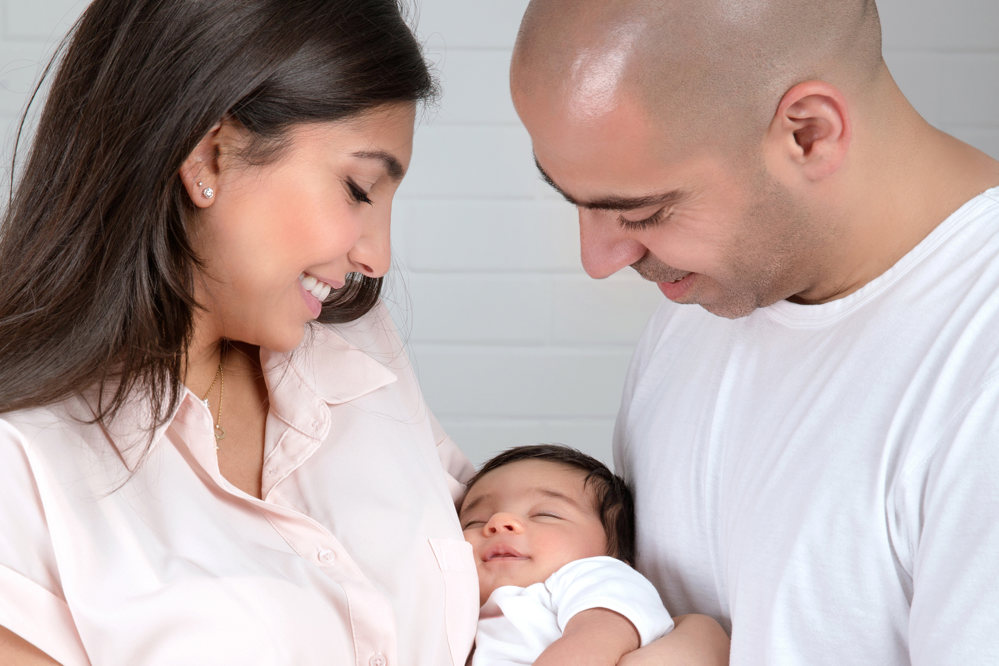 Happy couple holding a baby and smiling