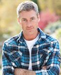 Young man in colorful shirt looks at camera with his arms crossed in front